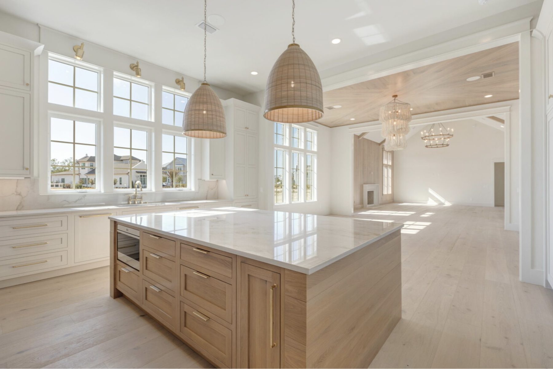 Open great-room kitchen with a white oak island and rattan pendants